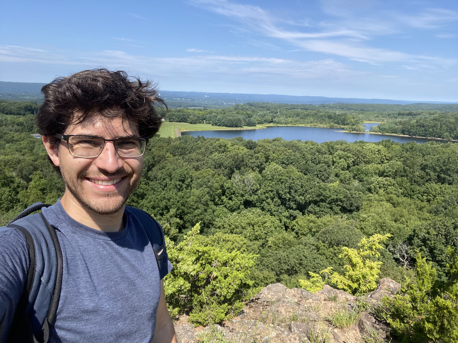 Selfie of Noah Houpt, PhD student at Yale University with trees and water and blue sky in the background