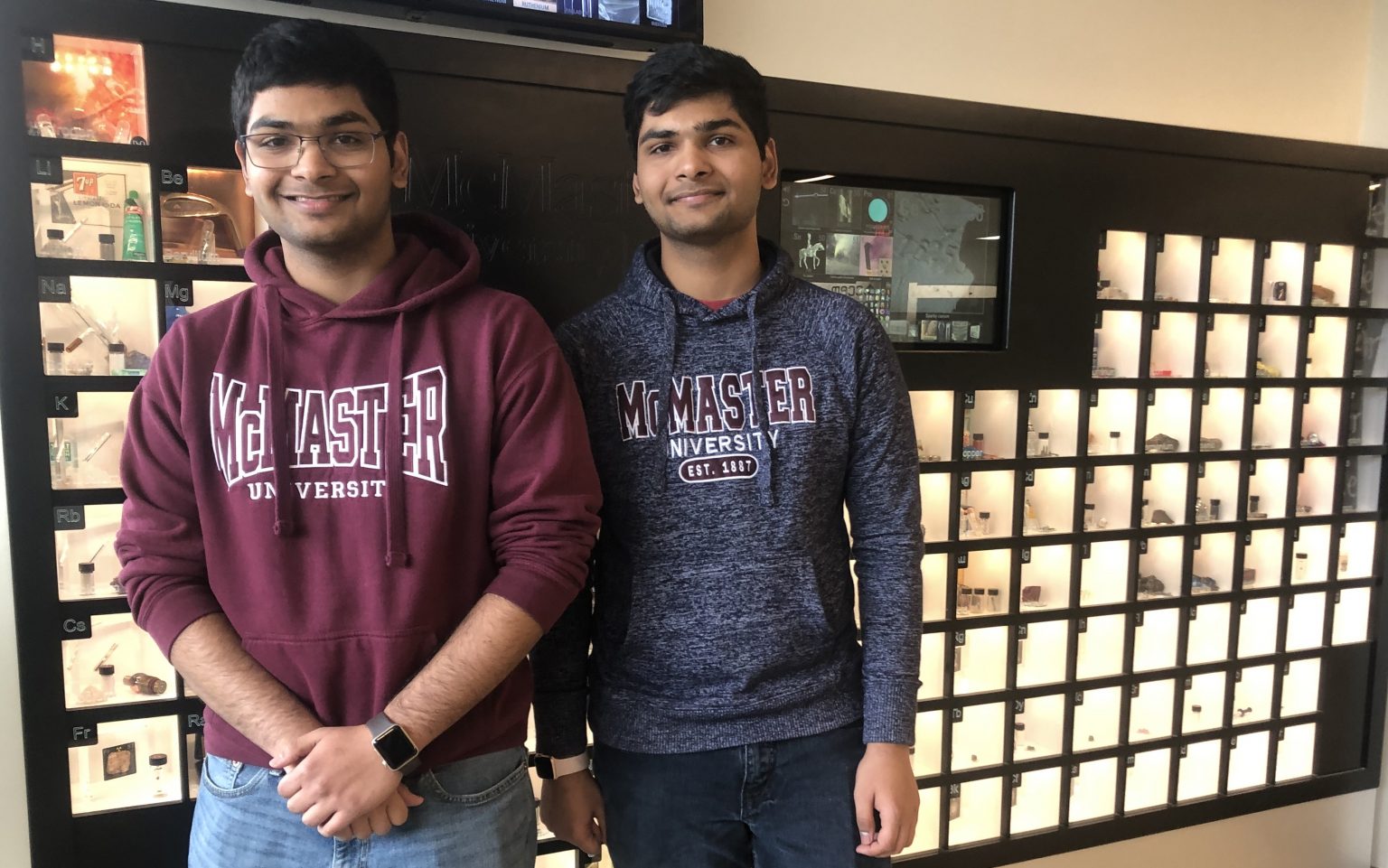 Patil brothers standing in front of the periodic table of elements in ABB