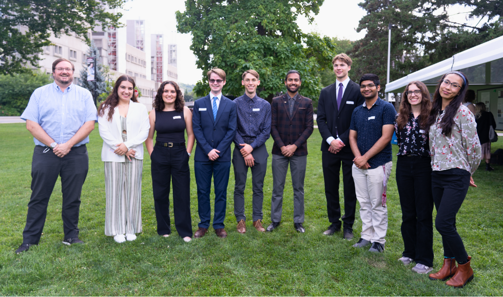 10 CNL-McMaster UG students standing on the lawn in a line smiling for the camera